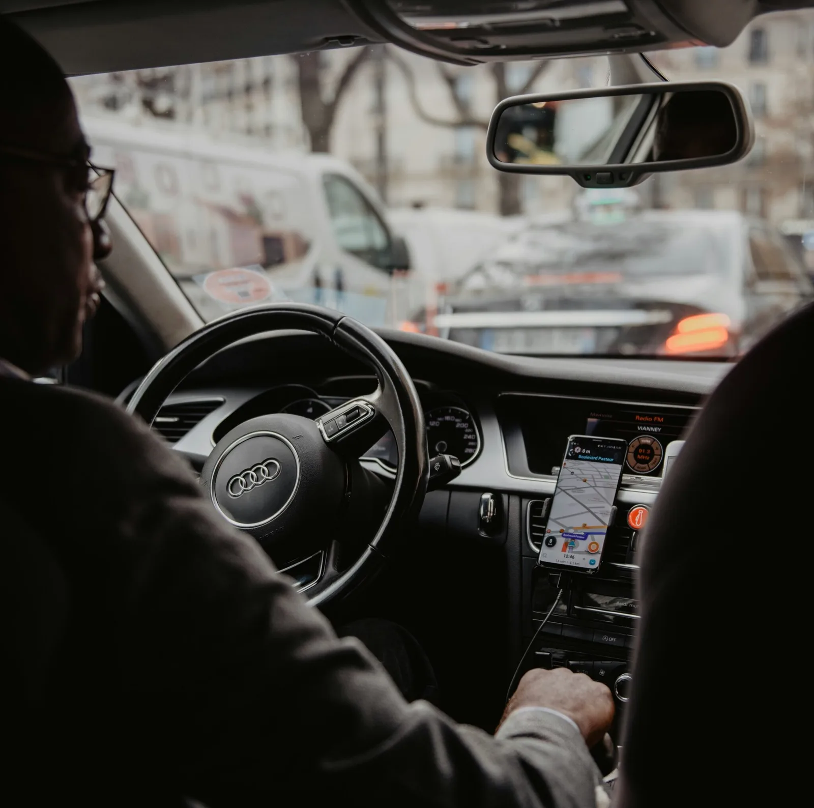 Schipholride chauffeur in pak achter het stuur, navigatie en kaart op het dashboard tijdens een rit